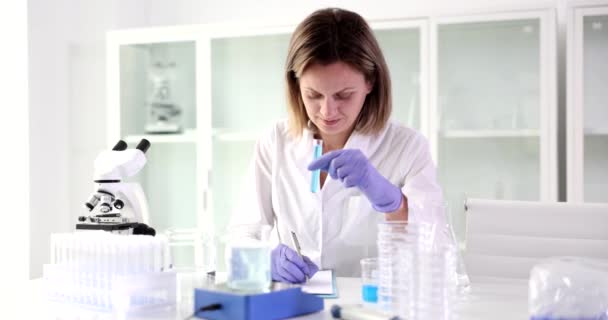 Женщина Лаборатории Держит Фляжку Голубым Образцом Пишет Крупный План Химическое — стоковое видео
