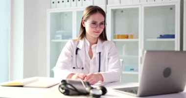 Genç doktor dizüstü bilgisayarın videosunda konuşuyor, yakın plan. Bir tıp uzmanının uzaktan konsültasyonu