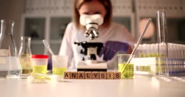 Üzerinde yazı analizi olan tahta küpleri, yakın plan. Laboratuvar asistanı mikroskoba ve teşhise bakıyor.