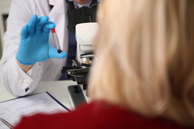 Laboratuvar asistanı antikorlar ve virüsler için kan analizi hazırlıyor. Hasta klinikte kan testi yaptırıyor.