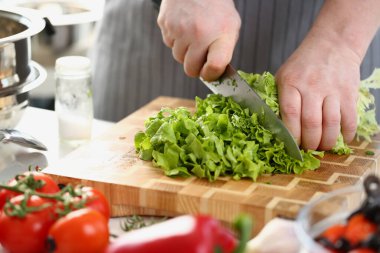 Önlüklü şef sebze ve yeşil salata keser. Yemek pişirmek için çevre dostu ürünler kavramı