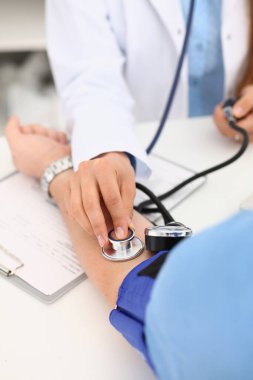 Kardiyolog doktor klinikte tonometresi olan hastaya kan basıncını ölçüyor. Atardamar hipertansiyonu tanısı ve basınçla ilgili sorunlar