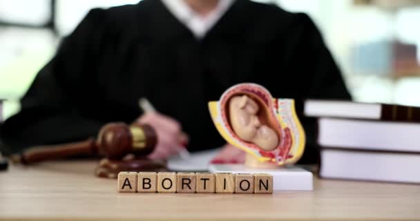 子宮の胎児のモデルと裁判官テーブルの上の単語中絶閉鎖4K映画スローモーション 中絶の概念に関する公式な禁止 — ストック動画