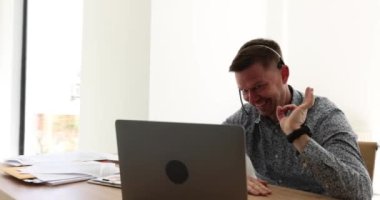Telefondaki gülümseyen pazarlamacı, kablosuz kulaklık takıyor ve dizüstü bilgisayarında video konferansı düzenliyor. Mutlu yönetici konuşuyor ve çevrimiçi istemciye danışıyor