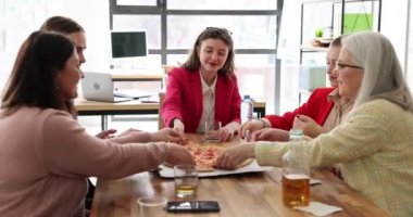 Ofisteki insanlar bir araya gelip masada pizza dilimlerini paylaşıyorlar. Takım üyeleri iş arasında birlikte yemek yer ve yemeğin tadını çıkarırlar.