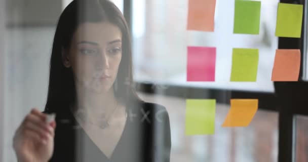 迷人的女经理在彩色玻璃贴纸上写下信息和提醒 创建一个待办事项列表 并构想新的业务构想 以启动 — 图库视频影像