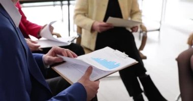 Grafikler ve farklı iş adamlarının elleri üzerinde gösterilen istatistiksel verilerin yakınlaştırılması. Şirketin mali verilerini tartışıyoruz.