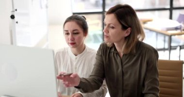 Yoğunlaşmış meslektaşlar masada oturmuş dizüstü bilgisayardaki projeyi tartışıyorlar. Seo, bayan öğrenci için eğitimini yönetiyor.