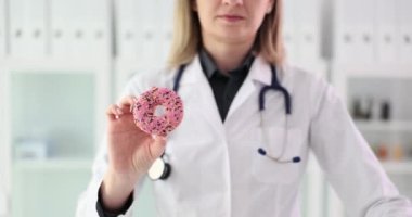 Doktor diyetisyen elinde tatlı bir çörek tutuyor ve jestten hoşlanmıyor. Sağlığa zararlı tatlı ve nişastalı gıdalar