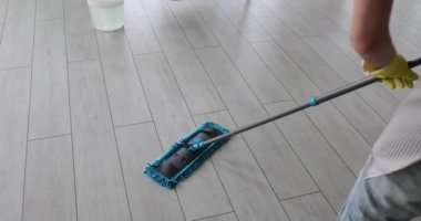 Kadın yerleri paspasla temizliyor. Temizlikçi ev işleri konseptine yardım ediyor.