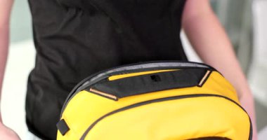 Kadın sarı sırt çantasından dizüstü bilgisayarı çıkarıyor. En iyi laptop sırt çantaları