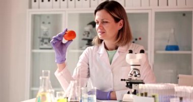 Laboratuvardaki kadın bilim adamı turuncu turunçgillere yakından bakıyor. Zehirli yiyecekler ve meyveler üzerine çalış