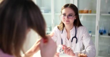 Doktor, klinikteki kadın hastaya kırık uçlar için ilaç veriyor. Saç restorasyonu ve kellik konsepti için farmakolojik ürünler