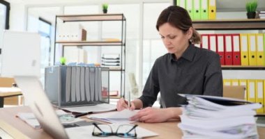 Düşünceli genç iş kadını ofis masasında finansal proje geliştiriyor. İş kadını kağıt projesinde muhasebe raporu hazırlıyor ve verileri düzenliyor