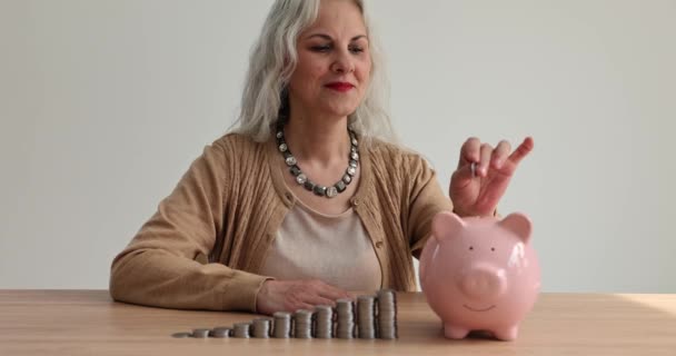 Happy Middle Aged Elderly Woman Puts Coin Piggy Bank Saves — Stock Video