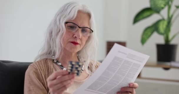 高齢女性は薬を保持し 医療指示を読みます 高齢者における薬の使用方法 — ストック動画