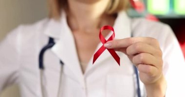 Dünya AIDS Günü 'nün sembolü olarak doktorun ellerinde kırmızı kurdele. Bağışıklık yetmezliği virüsünün yol açtığı bir hastalık.