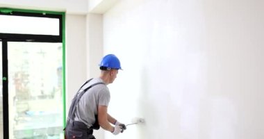 İnşaatçı evin duvarını paten fırçasıyla boyuyor. Dekorasyon ve iç dekorasyon kavramı