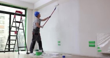 Boyacı duvarı silindirle beyaza boyar. Dairenin duvarlarını ya da tavanını boyamak