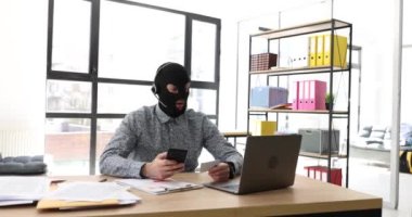 Kulaklıklı, akıllı telefonlu ve banka kartlı kar maskeli bir internet dolandırıcısı. Şebekede siber suçlar ve mali suçlar ve banka kartlarını hacklemenin yolları