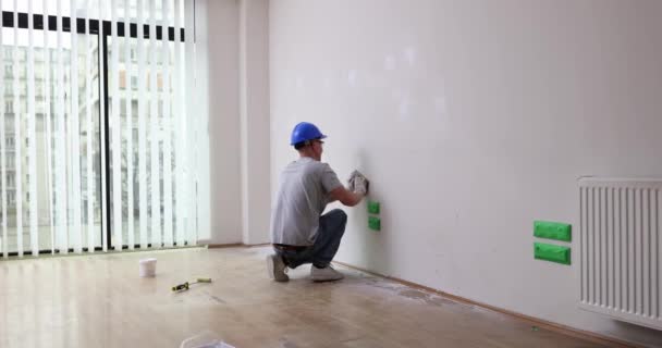 石膏ビルダーは サンドペーパーで壁を滑らかにします 家の中で絵を描くための壁の準備 — ストック動画