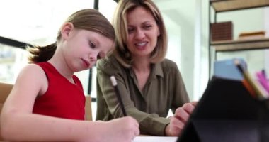 Küçük kız öğretmeniyle çalışıyor. Evde tablet kullanıyor. Film ağır çekimde. Okul konsepti için özel ders hazırlama