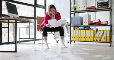 Çorap çalışmaları yapan çıplak ayaklı kadın şirket ofisindeki sandalyeye oturmuş kağıtları dağıtıyor. İş kadını şirket konferansı için bilgi hazırlıyor