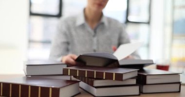 Kadın, aydınlık odada ekonomi araştırması yapan bir kitap sayfasını çeviriyor. İş kadını şirket ofisindeki ticari rehberde bilgi istiyor