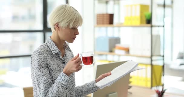 女人在公司的办公室里看商业报告 拿着茶杯 商务女士在工作休息期间为公司会议作准备 — 图库视频影像