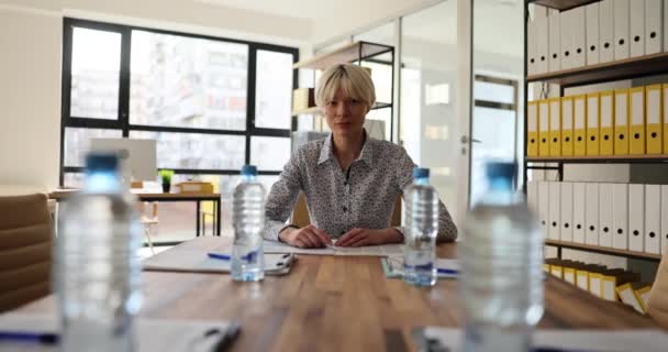 ブロンドのビジネスマンは 会議参加者がオフィスのボードテーブルに座って待っています 会社で新しいプロジェクトを発表する準備ができているビジネスの女性 — ストック動画