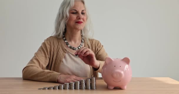 Šťastná Seniorka Dává Mince Prasátko Banky Dřevěného Stolu Cash Money — Stock video