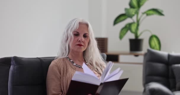 Gri Saçlı Yaşlı Kadın Evde Ağır Çekimde Koltukta Kitap Okuyor — Stok video
