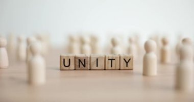 Sözcük birliği, tahta bloklardan ve masada pinli biblolardan oluşur. İnsanlar kalkınma ve destek için işbirliği yapıyor. Ortaklık kavramı