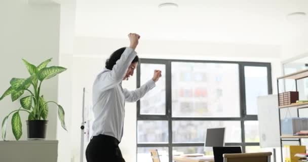 ハッピーマン社員が飛び込み会社のオフィススローモーションで頭の上に手を振る 若いマネージャーは成功した取り引きを祝う キャリア推進 — ストック動画
