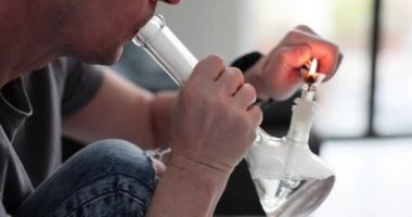 Adam ışık odasında psikoaktif maddeyle nargile içiyor. Bağımlı kişi uyuşturucu almak için cihaz kullanır. Tehlikeli bağımlılık belirtileri