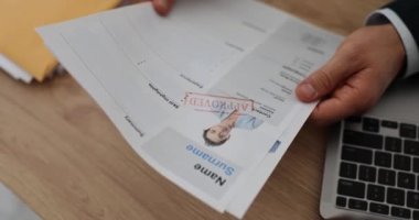 İK müdürü, ofis masasında boş yer için onaylanmış adayların özgeçmişlerini tutuyor. Patron şirket için profesyonel personel tutar. İstihdam süreci