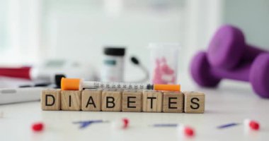 Tahta küplerden yapılmış ve üzerinde şırınga bulunan kelime diyabeti bulanık kapsüller ve masanın üzerindeki dambıllar. Klinikte insan hastalıklarının tedavisi