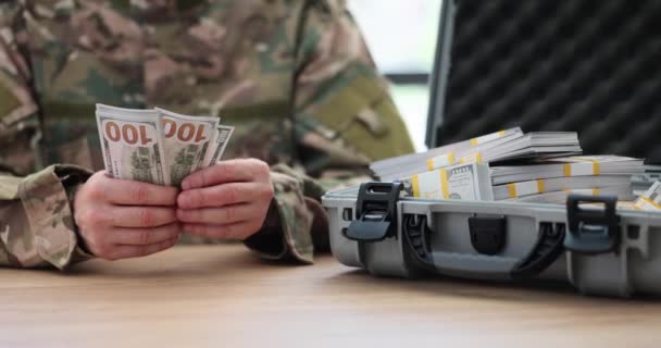 军官数着桌子旁的美元钞票 这些钞票几乎是开着的箱子里堆满了钱 身着制服的人用现金购买武器慢动作 — 图库视频影像
