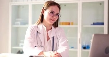 Profesyonel doktor bilgisayardaki görüntülü konuşma yoluyla hastayla konuşuyor. Kadın uzmanlar teşhisi ve tedaviyi yavaş çekimde anlatır.
