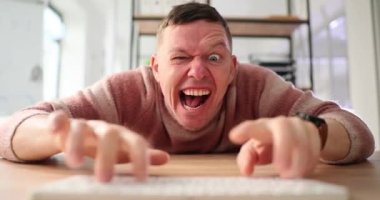 İnternette dolandırıcılık yapan heyecanlı adam ağır çekimde PC klavyesinde. Deli adam internette provokasyon hazırlıyor. Duygusal oyuncular odada oynar