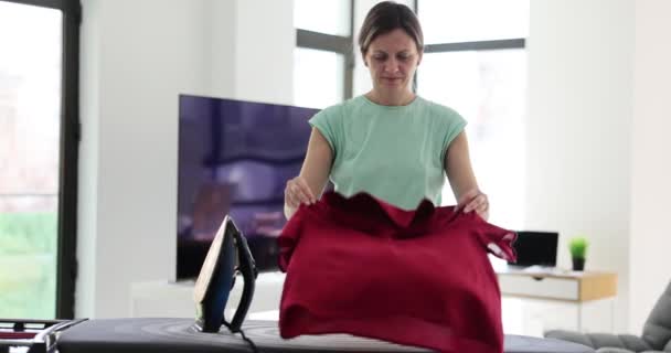 Κουρασμένη Γυναίκα Βάζει Μπορντό Μπλούζα Σιδερώστρα Στο Φωτεινό Δωμάτιο Του — Αρχείο Βίντεο