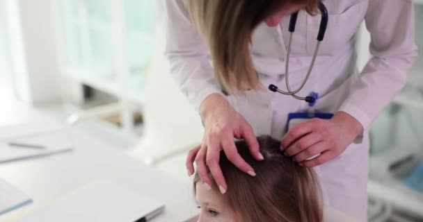 女性医師は小さな患者の髪に虫を探します 制服の専門家は 定期的に病院スローモーションで女子学生の健康と体の検査を行います — ストック動画
