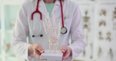Steteskoplu kadın doktor el iskeleti tutuyor. Profesyonel tıp alanında kol iskeleti öğrencilere daha yavaş çekimde sunuluyor.