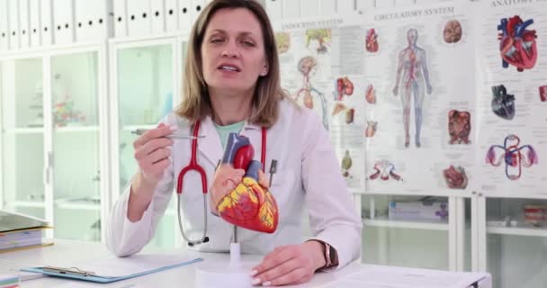 제복을 여의사는 인간의 심장의 인공적 모델을 검사한다 여성은 클리닉 교실에서 — 비디오
