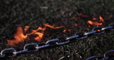 Spor egzersizleri için galvanize halat savaş zincirleri yanan siyah çimenler üzerinde yatar. Dayanıklı metal zincirler çimlerde ağır çekimde yatıyor.