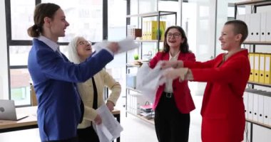 Neşeli meslektaşlar hafif ofisteki önemli projelerini bitirdikten sonra kağıtlarını fırlatırlar. Memnun genç adam ve kadınlar özgürce ve yavaş çekimde mutlu olurlar.