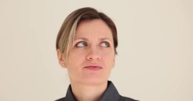 İlgili sarışın genç bayan etrafa bir göz atar. Mavi gözlü kadın gülümsüyor ve çevreyi beyaz duvara karşı ağır çekimde inceliyor.