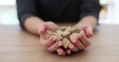 Kadın alfabe harfleriyle küçük tahta küpleri dağıtıyor. Çıplak manikürlü ve masa yüzeyinde ağır çekimde kelimeler yazan kadın elleri.