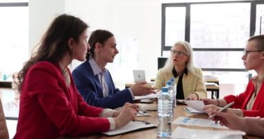 Yoğunlaşmış meslektaşlar konferansta yeni bir projenin hayata geçirilmesi konusunda fikirler öne sürdüler. Çalışanlar büyük masa başındaki koltuklarda oturan sorunları tartışıyor