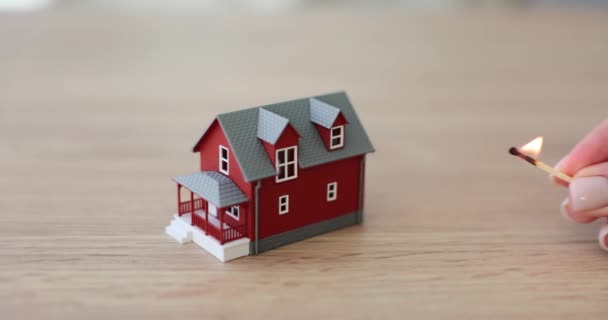 女性的手把点燃的匹配家庭住房的小细节模型推荐保险 木制桌子上立着带有红墙的公寓的缩微胶片 — 图库视频影像